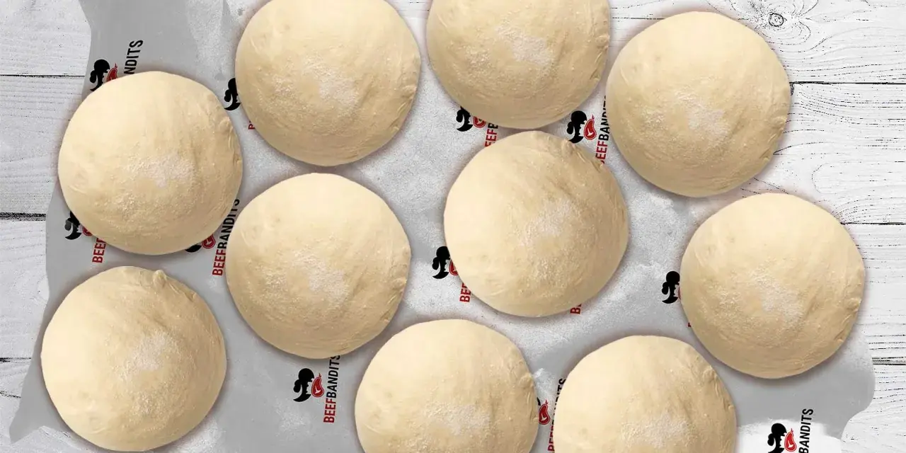Neun runde, helle pizza teiglinge liegen auf Backpapier mit dem Logo "Beefbandits" auf einer Holzoberfläche.