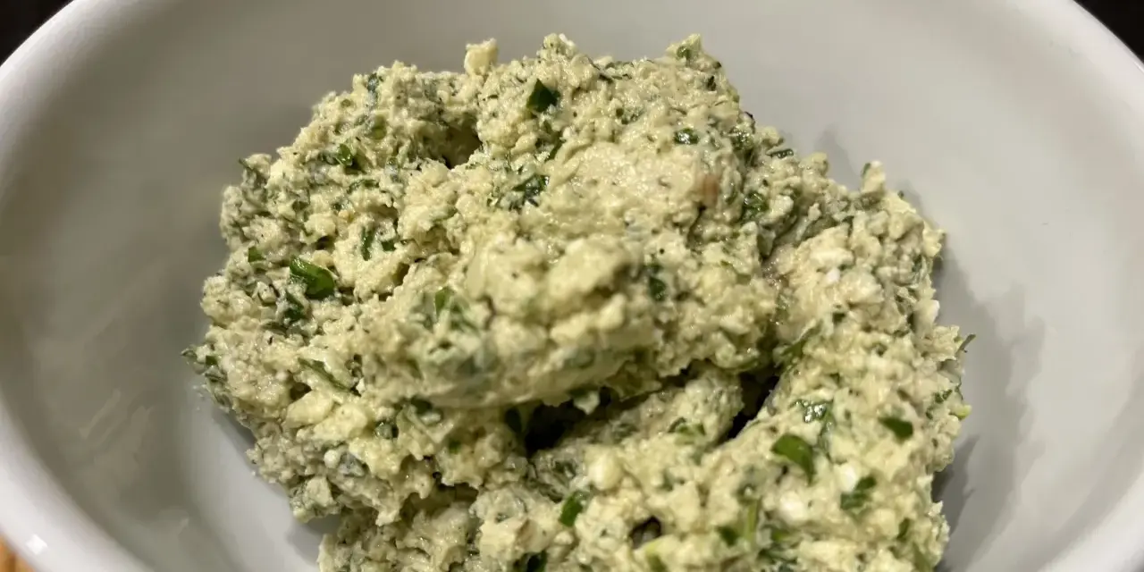 Ein cremiger Käseaufstrich mit Kräutern, wie er für ein Moretum Rezept typisch ist.