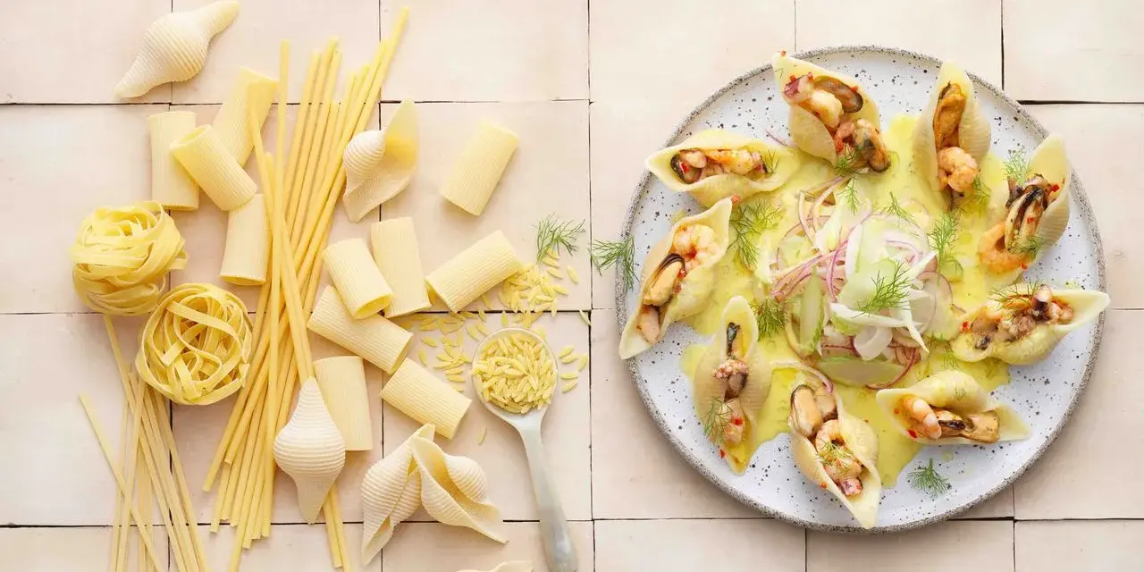 Gefüllte Conchiglioni mit Meeresfrüchten, ein köstliches italienisches Rezept. Daneben verschiedene italienische Pasta-Sorten.