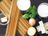 Zutaten für eine cremige Gorgonzola-Sauce: bunte Spaghetti, Butter, Zwiebel, Zitrone, Basilikum und Gorgonzola.