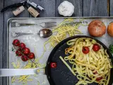 Frische Nudeln aus Hartweizengries, Tomaten, Zwiebeln und Knoblauch auf einem Blech. Ein Festmahl für Genießer!