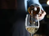 Weißwein wird in ein Glas gegossen. Die natürlichen wein zutaten sind im Glas sichtbar.