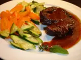 Ossobuco vom Rind auf sizilianische Art, zart geschmort in dunkler Sauce, serviert mit Karotten und Zucchini.