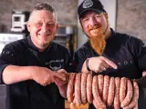 Zwei Metzger präsentieren stolz eine Reihe von frisch gefüllten Salsiccia mit Haut, bereit zum Braten.