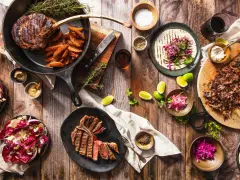 Ein Sommelier wählt den perfekten Wein zu saftigen Steaks, Beilagen und frischen Salaten.