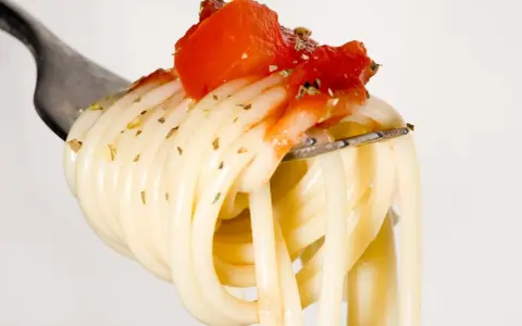Eine Gabel mit Spaghetti, belegt mit Tomaten und Kräutern. Ein Vorgeschmack auf die besten italienischen Pasta Rezepte.