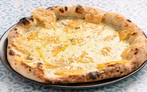 Eine köstliche Pizza Formaggi mit geschmolzenem Käse und knusprigem Rand, serviert auf einem Teller mit blau-weißem Muster.