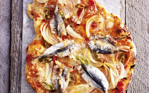 Eine rustikale Sardellen Pizza mit Zwiebeln und grünen Paprikastreifen, auf einem Holzbrett serviert.