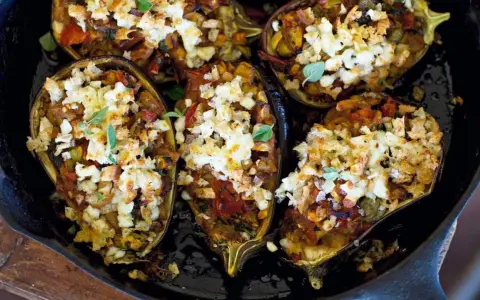 Melanzane ripiene, gefüllt mit Gemüse und Käse, in einer Gusseisenpfanne.