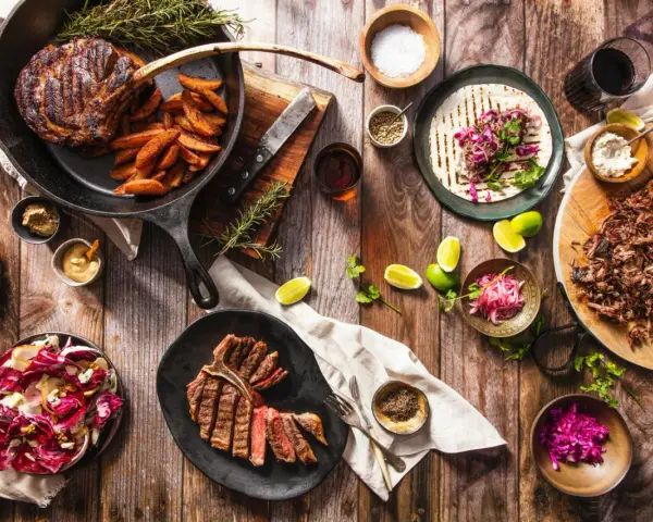 Ein Sommelier wählt den perfekten Wein zu saftigen Steaks, Beilagen und frischen Salaten.