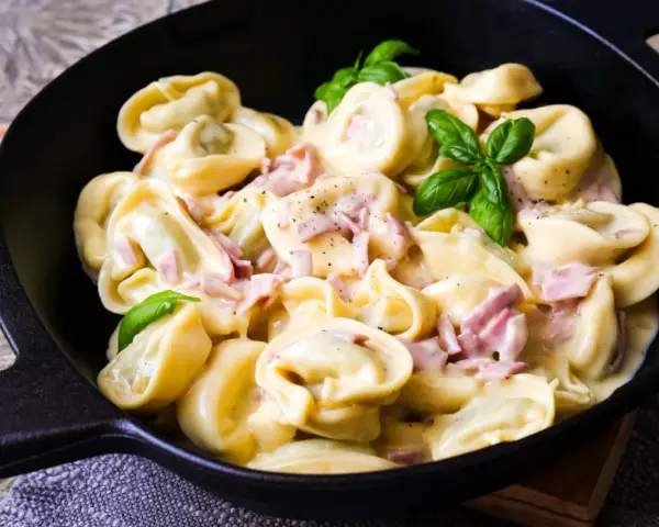 Köstliche Tortellini in cremiger Sauce mit Schinken und frischem Basilikum. Ein einfaches Gericht, das zu den beliebtesten Tortellini Rezepten zählt.