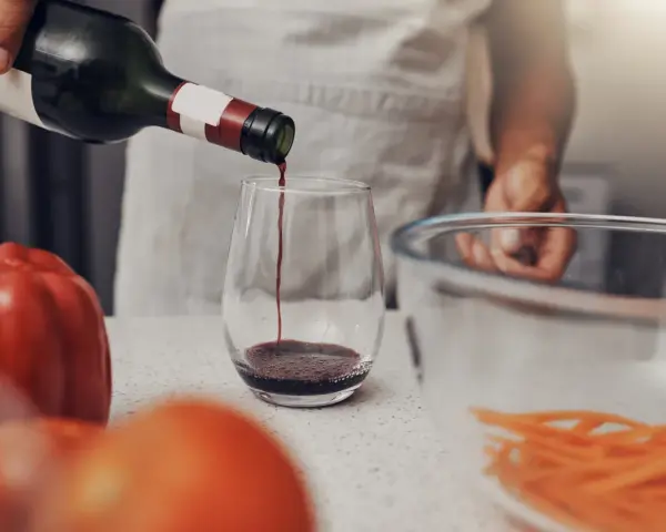 Rotwein wird in ein Glas gegossen, bereit für die Zubereitung eines köstlichen Gerichts. Die Frage, welchen Wein zum Kochen, ist nun beantwortet.