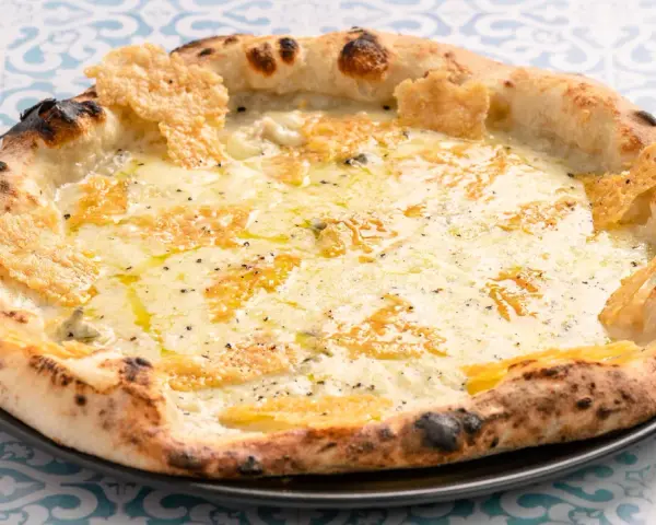 Eine köstliche Pizza Formaggi mit geschmolzenem Käse und knusprigem Rand, serviert auf einem Teller mit blau-weißem Muster.