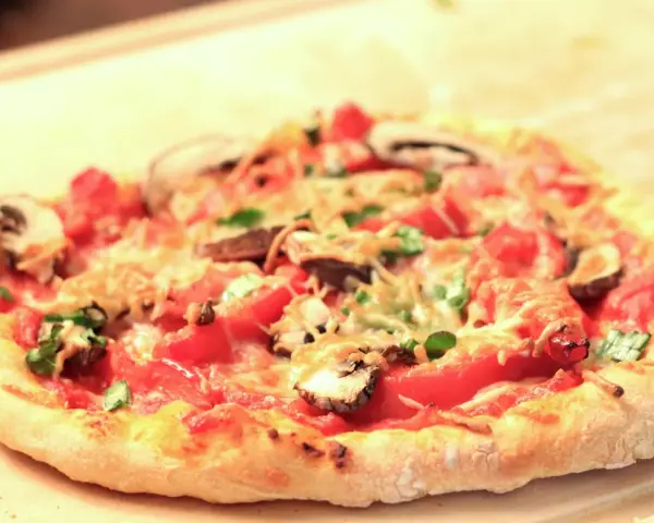 Eine köstliche Pizza mit Pilzen und Tomaten auf einem luftigen pizzateig mit lievito madre, bereit zum Genießen.