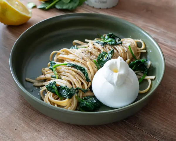 Pasta mit Spinat und einer cremigen Burrata, garniert mit frisch gemahlenem Pfeffer. Ein Genuss für jeden Tag.