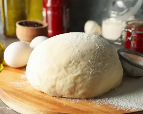 Frischer, fluffiger Teig für schnellen Pizzagenuss liegt bereit. Zutaten wie Eier, Öl und Gewürze deuten auf eine köstliche Pizza hin.