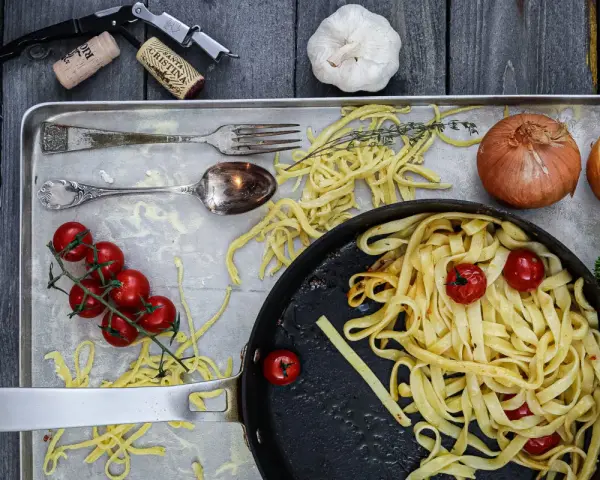 Frische Nudeln aus Hartweizengries, Tomaten, Zwiebeln und Knoblauch auf einem Blech. Ein Festmahl für Genießer!