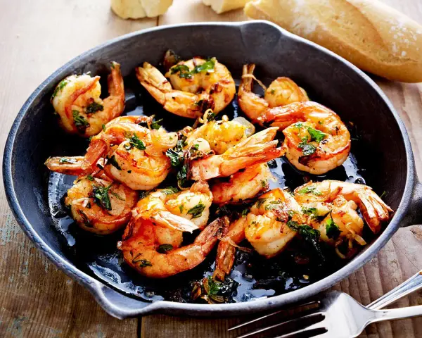 Saftige Garnelen in Knoblauchöl, ein Klassiker der italienischen scampi rezepte. Dazu Baguette.