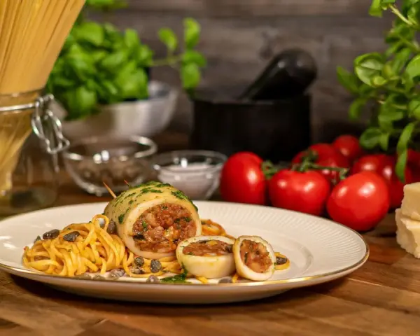 Seppie ripiene auf Pasta mit Kapern, Tomaten und Parmesan.
