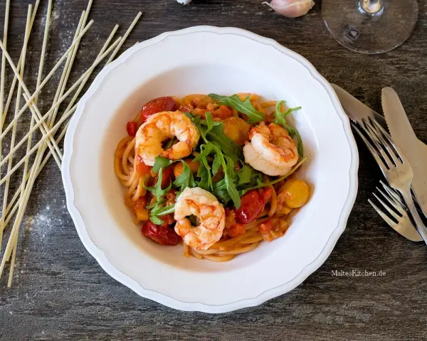 Ein köstliches garnelen italienisch rezept: Spaghetti mit Garnelen, Kirschtomaten und Rucola in einer cremigen Sauce.