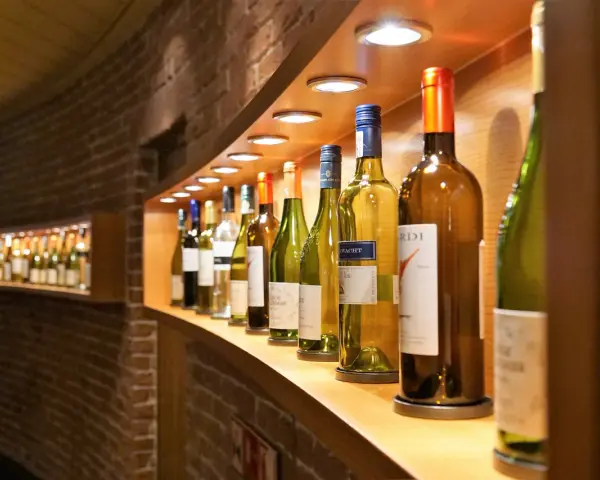 Eine Reihe von Wein- und Sektflaschen, einige davon sind bereits geöffnet. Die Frage, ob Rotwein schlecht werden kann, beschäftigt viele Weinliebhaber.