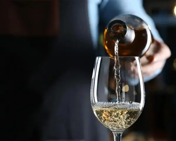 Weißwein wird in ein Glas gegossen. Die natürlichen wein zutaten sind im Glas sichtbar.