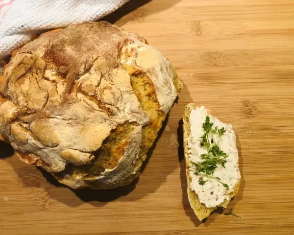 Ein rustikales, frisch gebackenes italienisches Brot Rezept, das genial einfach ist. Daneben ein Stück Brot mit Frischkäse und Kresse.
