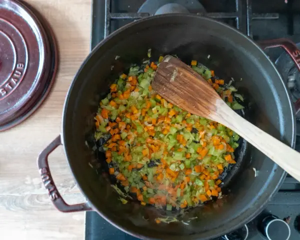 Würziges Sofrito Rezept: Karotten, Sellerie und Zwiebeln werden in einem gusseisernen Topf angedünstet.