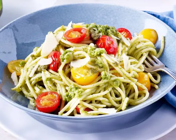 Spaghetti mit cremigem Avocado Pesto, Kirschtomaten und Parmesan.