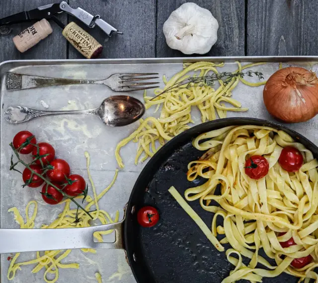 Frische Nudeln aus Hartweizengries, Tomaten, Zwiebeln und Knoblauch auf einem Blech. Ein Festmahl für Genießer!