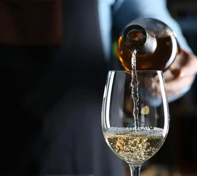 Weißwein wird in ein Glas gegossen. Die natürlichen wein zutaten sind im Glas sichtbar.