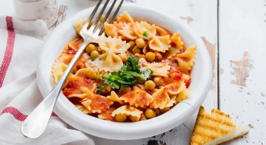 Farfalle-Pasta mit Kichererbsen in Tomatensauce, garniert mit Petersilie und Parmesan. Ein einfaches ceci rezept, perfekt für ein schnelles Mittagessen.