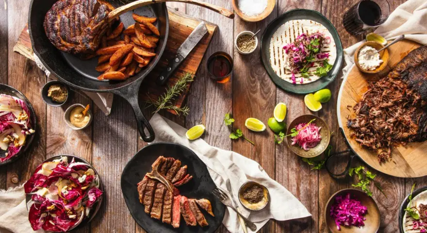 Ein Sommelier wählt den perfekten Wein zu saftigen Steaks, Beilagen und frischen Salaten.