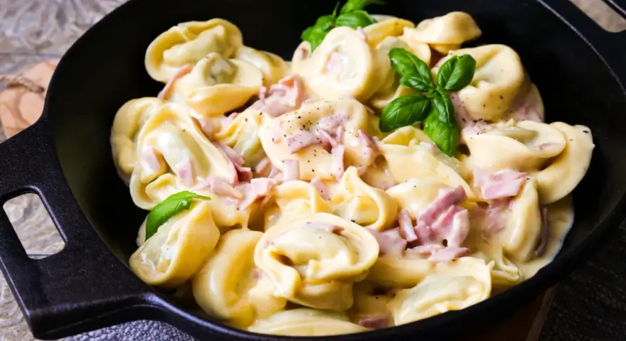 Köstliche Tortellini in cremiger Sauce mit Schinken und frischem Basilikum. Ein einfaches Gericht, das zu den beliebtesten Tortellini Rezepten zählt.