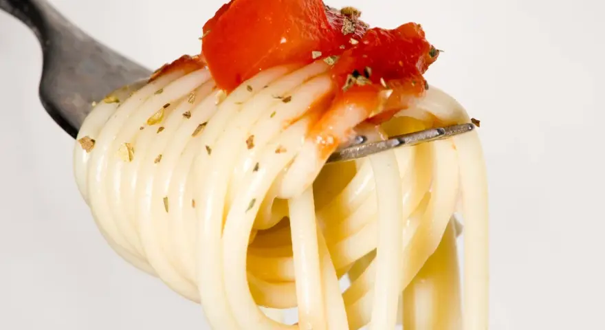 Eine Gabel mit Spaghetti, belegt mit Tomaten und Kräutern. Ein Vorgeschmack auf die besten italienischen Pasta Rezepte.