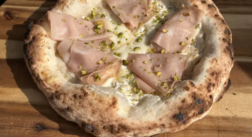 Frisch gebackener Pizzateig mit Mortadella und Pistazien. Ein Genuss, der das Pizzabacken zu einem Erlebnis macht.