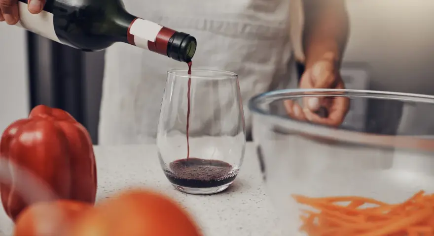 Rotwein wird in ein Glas gegossen, bereit für die Zubereitung eines köstlichen Gerichts. Die Frage, welchen Wein zum Kochen, ist nun beantwortet.
