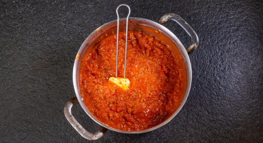 Herzhaftes Ragu in einem Topf, bereit für ein köstliches Ragu Rezept. Ein Löffel mit Butter liegt darin.