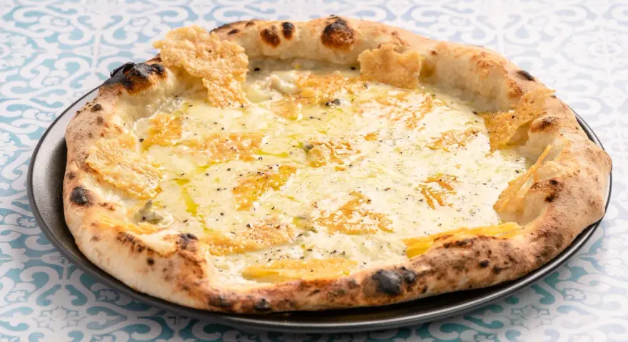 Eine köstliche Pizza Formaggi mit geschmolzenem Käse und knusprigem Rand, serviert auf einem Teller mit blau-weißem Muster.