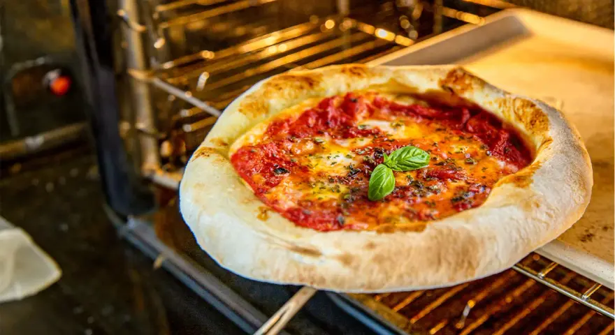 Eine köstliche Pizza im Backofen, mit geschmolzenem Käse und frischem Basilikum.