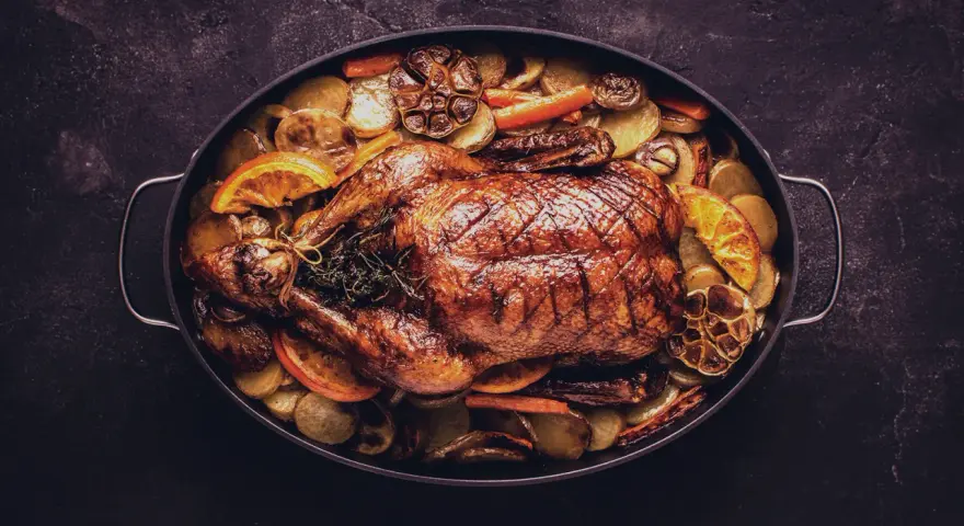 Brathähnchen mit Kartoffeln, Karotten, Orangen und Knoblauch. Ein Festmahl, das perfekt zu einem Glas Wein zu Ente passt.