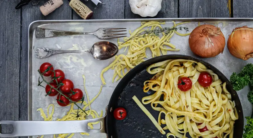 Frische Nudeln aus Hartweizengries, Tomaten, Zwiebeln und Knoblauch auf einem Blech. Ein Festmahl für Genießer!