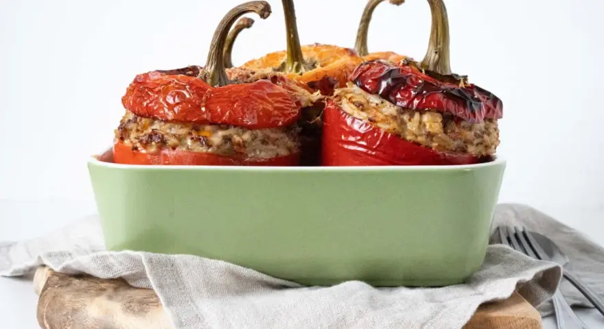 Saftige peperoni ripieni, gefüllt mit Hackfleisch und Reis, in einer grünen Auflaufform.