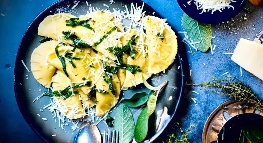 Frische Ravioli, ein italienisches Gericht, mit geriebenem Parmesan und Kräutern garniert. Das Ravioli-Teig Rezept italienisch ist hier perfekt umgesetzt.