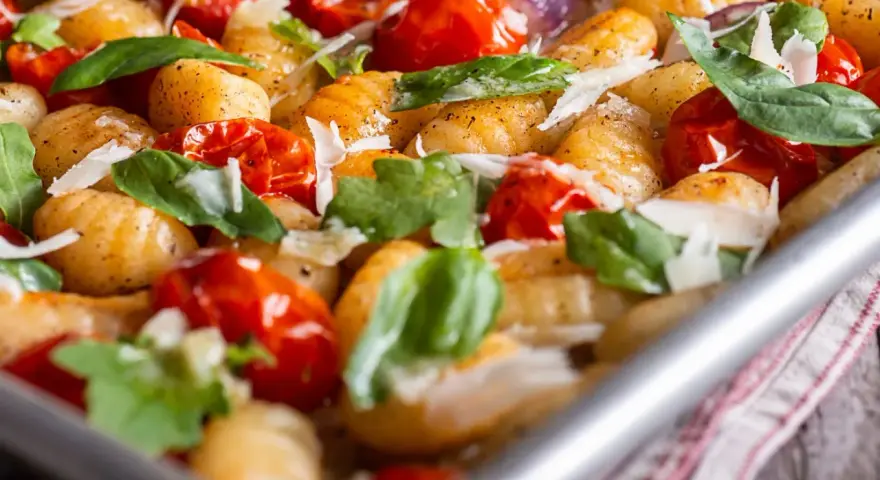 Gebackene Gnocchi mit Kirschtomaten, Basilikum und Parmesan. So sehen köstliche Gnocchi aus, wenn sie im Ofen mit frischen Zutaten zubereitet werden.