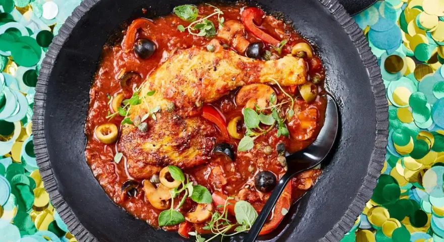Herzhaftes Pollo Cacciatore in Tomatensauce mit Oliven, Kapern und Pilzen, garniert mit frischen Kräutern.