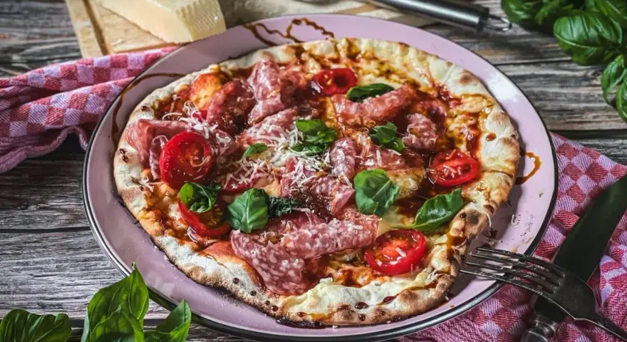 Leckere italienische Pizza mit Salami, Tomaten und Basilikum. Ein wahrer Genuss für alle, die italienische Rezepte lieben.
