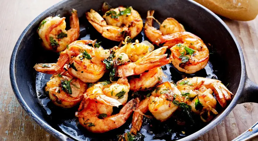 Saftige Garnelen in Knoblauchöl, ein Klassiker der italienischen scampi rezepte. Dazu Baguette.