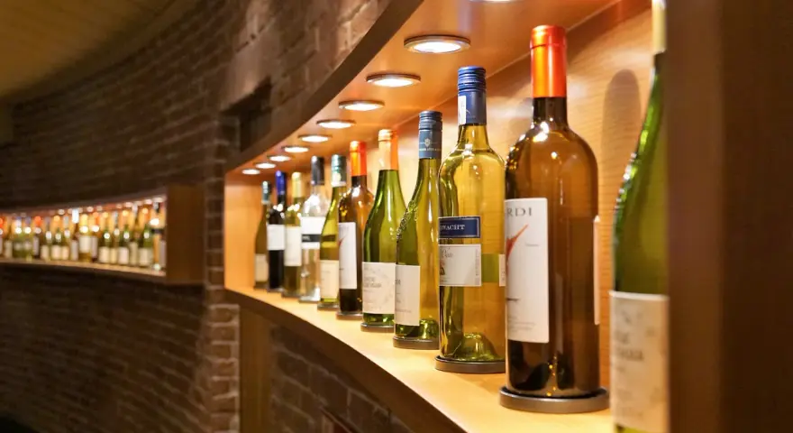 Eine Reihe von Wein- und Sektflaschen, einige davon sind bereits geöffnet. Die Frage, ob Rotwein schlecht werden kann, beschäftigt viele Weinliebhaber.