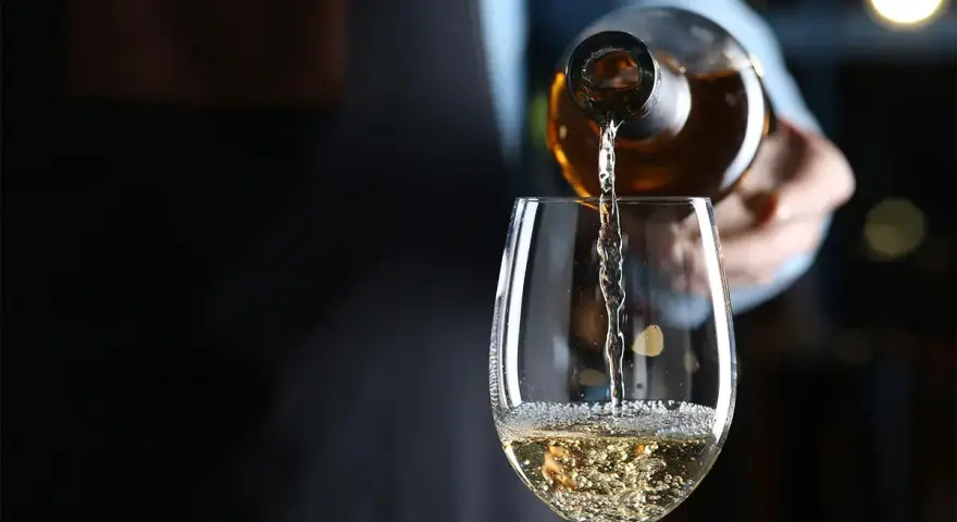 Weißwein wird in ein Glas gegossen. Die natürlichen wein zutaten sind im Glas sichtbar.